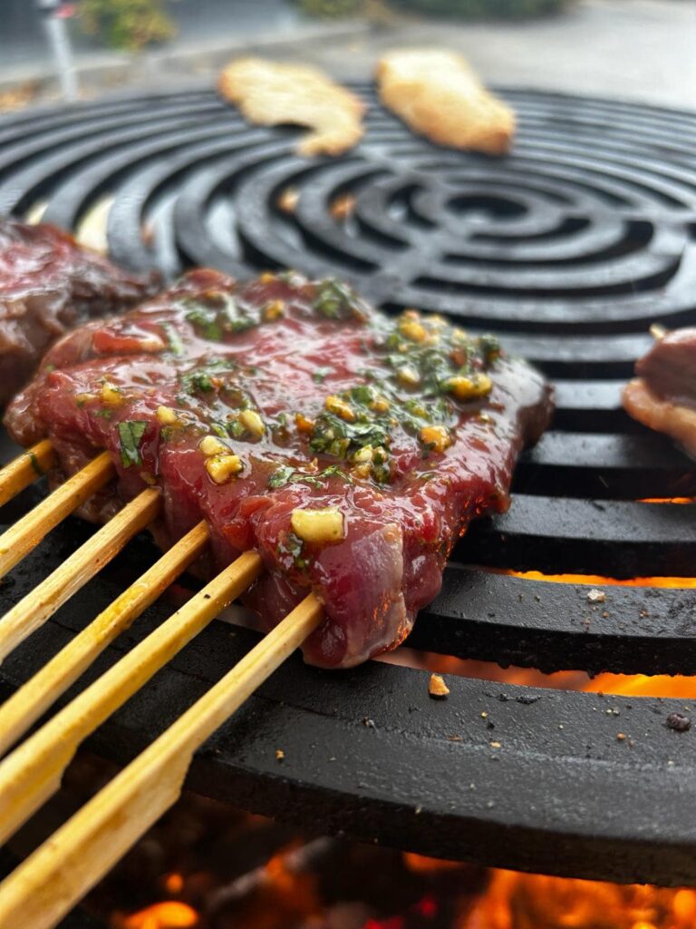 Grillade de bœuf marinée à l'ail sur barbecue au feu Brochette de bœuf marinée à l'ail et aux herbes grillant sur un barbecue au-dessus de flammes vives.