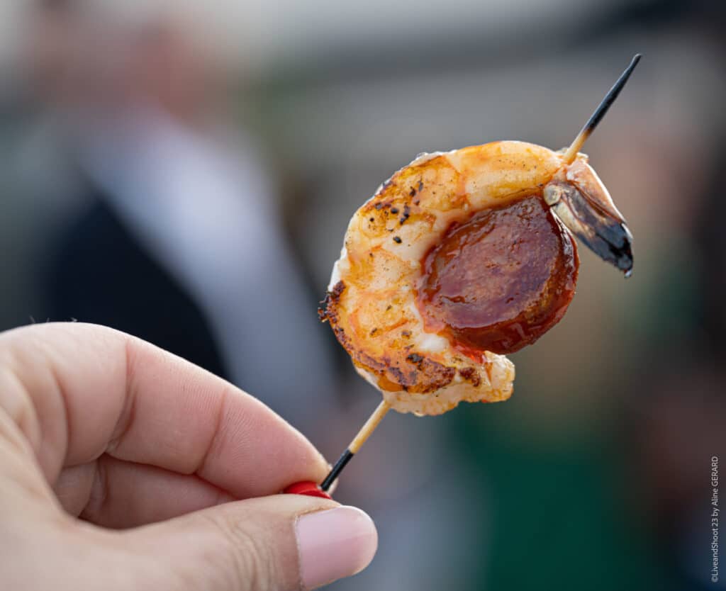 Brochette Crevette Chorizo Grillée pour Apéritif Brochette apéritive de crevette grillée et chorizo tenue à la main lors d'un cocktail dînatoire.