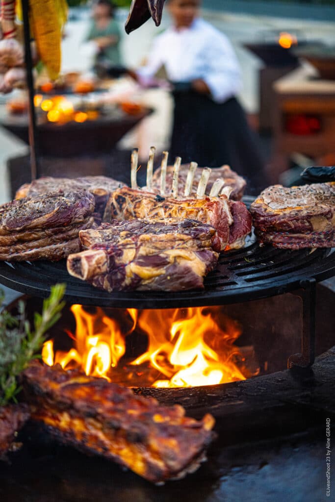Grillade au Feu de Bois : Côte de Bœuf et Tomahawk Côte de bœuf et tomahawk grillant sur un feu de bois vif lors d'un barbecue gastronomique en plein air.